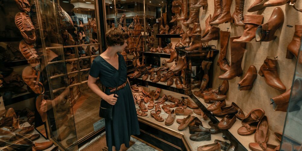 woman in black dress standing in front of brown leather shoes